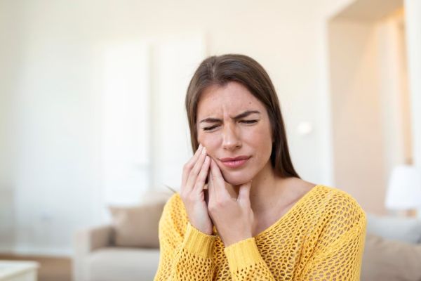 young woman suffering from terrible strong teeth pain