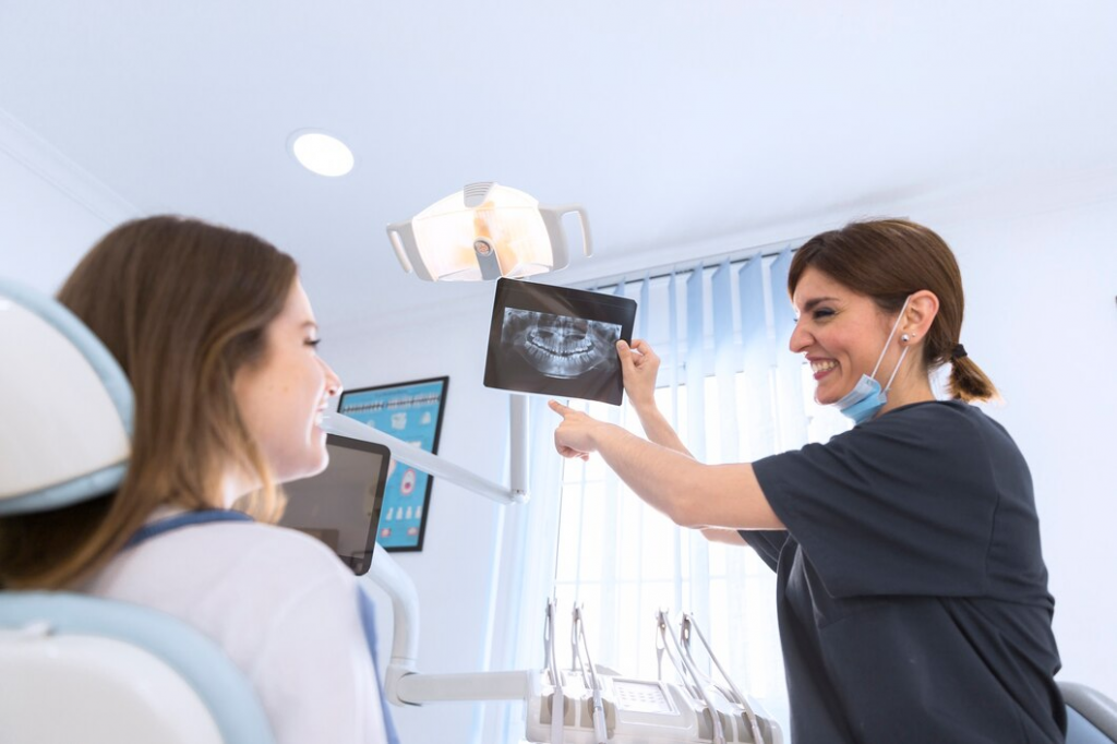 Happy smiling female dentist showing dental x-ray to patient